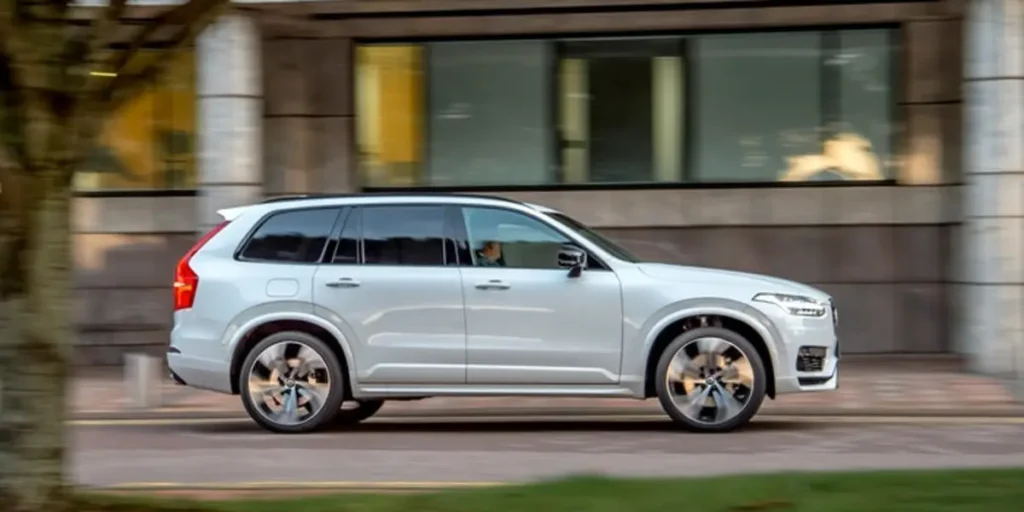 White Volvo XC90 driving on a city street.